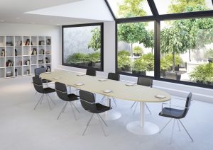 longue table ovale de réunion avec grandes fenêtres qui donnent sur une cour